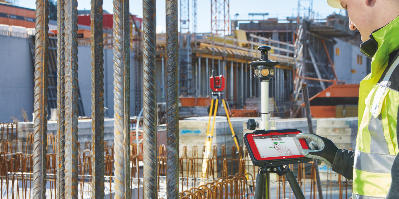 Zwei Mitarbeiter messen vor Ort mit einer Totalstation Gebäudetechnik-Haltevorrichtungen ein