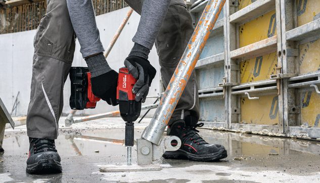 Ein Arbeiter installiert auf einer Baustelle eine Schalung mit Hilti Nuron Akku-Schlagschrauber SIW 8 und Betonschraube / Schraubanker HUS4-H
