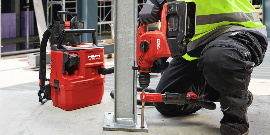Arbeiter bohrt Grundplatte mit Hilti TE 30-22 Akku-Bohrhammer und VC 10-22