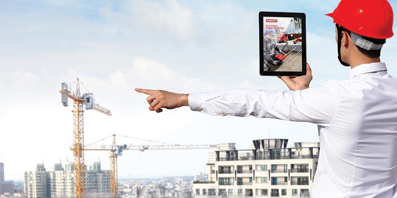 Rear view of architect looking tablet pc and comparing housing project with building