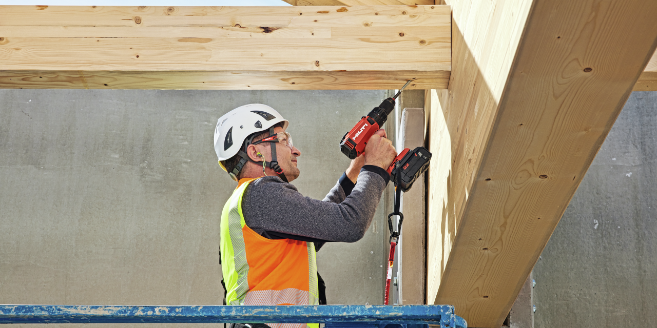 Arbeiter auf der Baustelle bei der Befestigung eines Holzbalkens