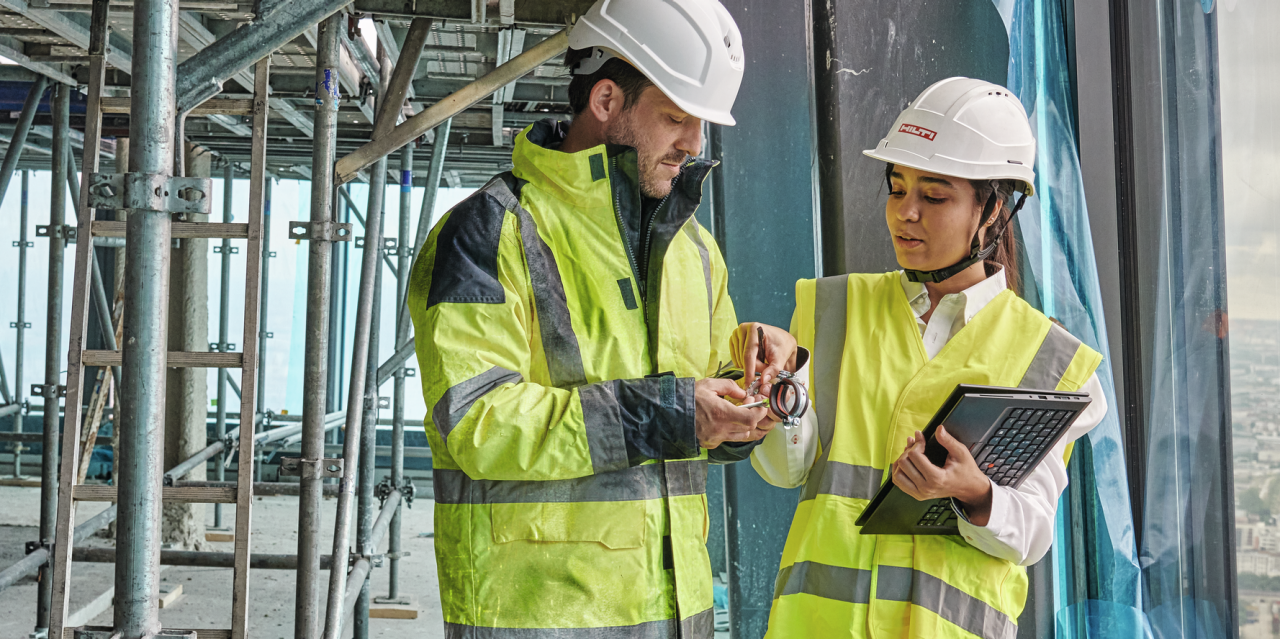 Außendienstmitarbeiterin spricht mit einem Kunden auf der Baustelle und zeigt ihm das MEP-Sortiment an Verbrauchsmaterialien 