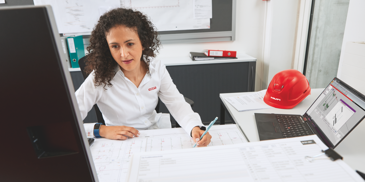 Hilti Ingenieur im Büro mit Werkstattzeichnungen im Vordergrund